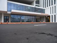 a large building that has a glass facade and lots of orange cones in front of it