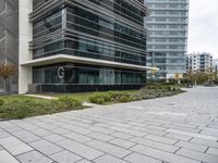 the sidewalk in front of some buildings with a clock on it on the side of a building