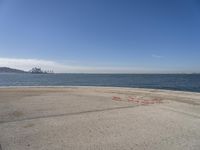 a person sitting on the beach in front of the ocean, looking at the water