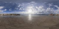 a view of a beach in front of the ocean and clouds from a fish eye lens