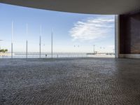 a view down a brick walkway with light poles on either side and in the background, a bright blue sky