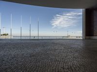 a view down a brick walkway with light poles on either side and in the background, a bright blue sky