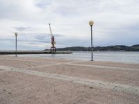 an empty waterfront with traffic lights and a crane in the background on a cloudy day