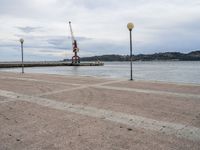 an empty waterfront with traffic lights and a crane in the background on a cloudy day