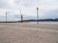 an empty waterfront with traffic lights and a crane in the background on a cloudy day