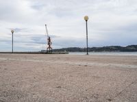 an empty waterfront with traffic lights and a crane in the background on a cloudy day