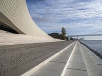 the walkway has water on it and a big bridge is in the background in this image