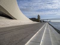 the walkway has water on it and a big bridge is in the background in this image