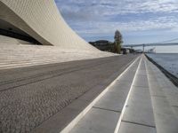 the walkway has water on it and a big bridge is in the background in this image