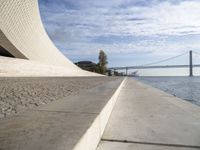 the walkway has water on it and a big bridge is in the background in this image