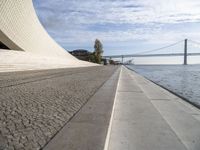 the walkway has water on it and a big bridge is in the background in this image