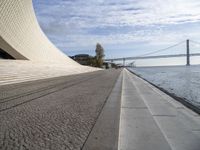 the walkway has water on it and a big bridge is in the background in this image