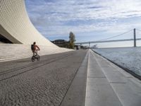 the walkway has water on it and a big bridge is in the background in this image