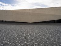 a street filled with cobblestones and concrete building with a sky in the background