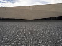 a street filled with cobblestones and concrete building with a sky in the background