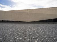 a street filled with cobblestones and concrete building with a sky in the background