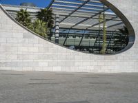 a person riding on a skateboard in front of a building with a big curved building