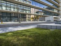 a picture of an office building near a sidewalk with benches and grass in front of it