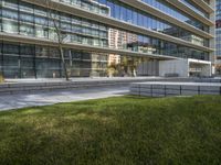 a picture of an office building near a sidewalk with benches and grass in front of it