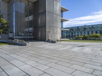 the courtyard features a few of small planters with plants sitting outside of it and grass, along side a building