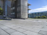 the courtyard features a few of small planters with plants sitting outside of it and grass, along side a building