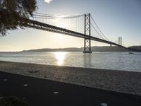 a view of a bridge across the ocean at sunset in a park with grass and shrubbery