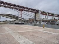 many boats are docked at the shore under a bridge that's made of concrete bricks