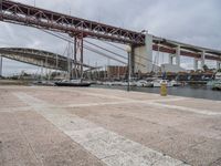 many boats are docked at the shore under a bridge that's made of concrete bricks