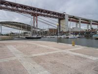 many boats are docked at the shore under a bridge that's made of concrete bricks