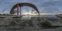 a panorama of the bay that is under a bridge at dusk, and there are small boats in the harbor