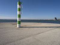 a green and white pole on a pier next to the water that reads beach road