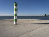 a green and white pole on a pier next to the water that reads beach road