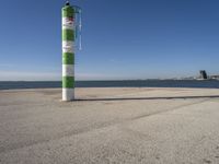 a green and white pole on a pier next to the water that reads beach road