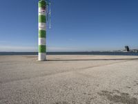 a green and white pole on a pier next to the water that reads beach road