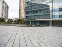 an empty concrete and glass building with cars parked in front of it on a sunny day