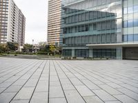 an empty concrete and glass building with cars parked in front of it on a sunny day