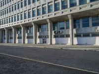 a tall building with concrete pillars in front of it that has closed doors with windows