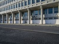 a tall building with concrete pillars in front of it that has closed doors with windows