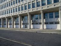 a tall building with concrete pillars in front of it that has closed doors with windows