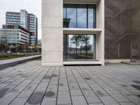 the building's exterior features a grey stone pattern on the outside, with windows, trees and benches surrounding