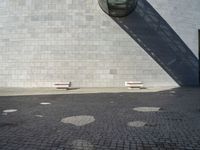 two white seats sitting on a stone floor in front of a building with a street lamp in the background