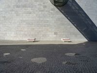 two white seats sitting on a stone floor in front of a building with a street lamp in the background