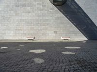 two white seats sitting on a stone floor in front of a building with a street lamp in the background