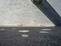 two white seats sitting on a stone floor in front of a building with a street lamp in the background