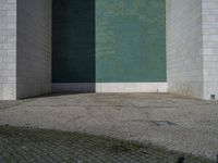 the corner of the building with the floor in the middle, the wall made from glass has tiles painted in blue, green, and white and silver, and black