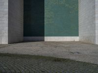 the corner of the building with the floor in the middle, the wall made from glass has tiles painted in blue, green, and white and silver, and black