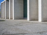 the corner of a concrete building is clearly visible on the ground, and there are two people walking past