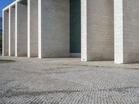 the corner of a concrete building is clearly visible on the ground, and there are two people walking past