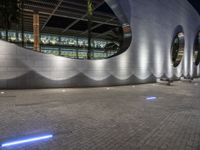 a street scene with focus on a circular wall and lights at night time, looking like they could fly