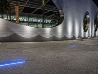 a street scene with focus on a circular wall and lights at night time, looking like they could fly